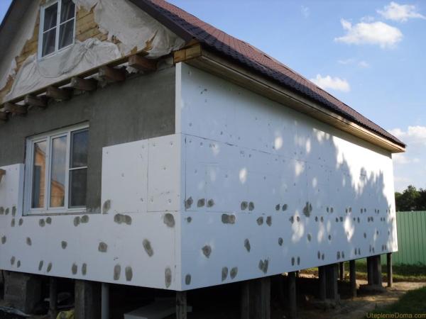 Maison en bois isolée avec des panneaux de mousse. Le mortier de ciment couvre les capuchons des chevilles en plastique qui retiennent le matériau