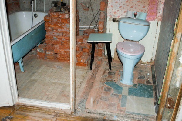 Une salle de bain après la démolition d'un mur de briques.