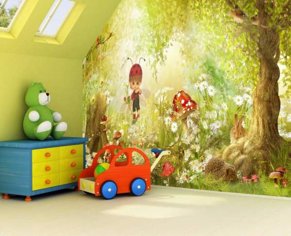 La photo montre l'intérieur de la chambre des enfants, décoré de peintures murales représentant une forêt claire le long de laquelle le bébé marche et regarde les animaux