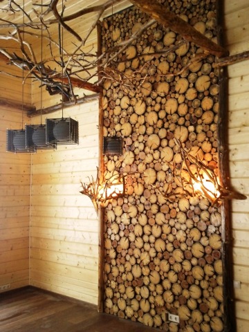 Un grand panneau en bois sur une partie de l'un des murs de la maison peut également être décoré avec des lampes
