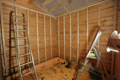 Sur la photo, nous voyons la préparation des murs d'une maison en bois, avec un revêtement en placoplâtre