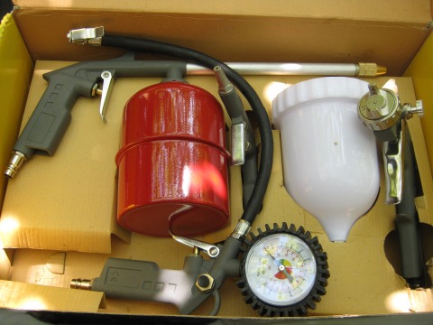 Gedemonteerd verfspuitpistool en nippel met manometer voor het oppompen van wielen
