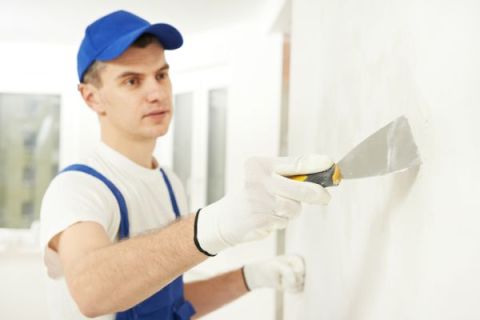 Nettoyage avec une spatule étroite sur la surface du mur.